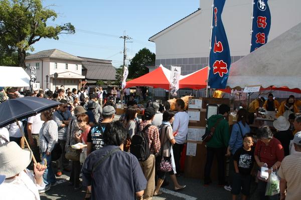 赤と白のテントが張られた前に多くの人が並んでいる写真